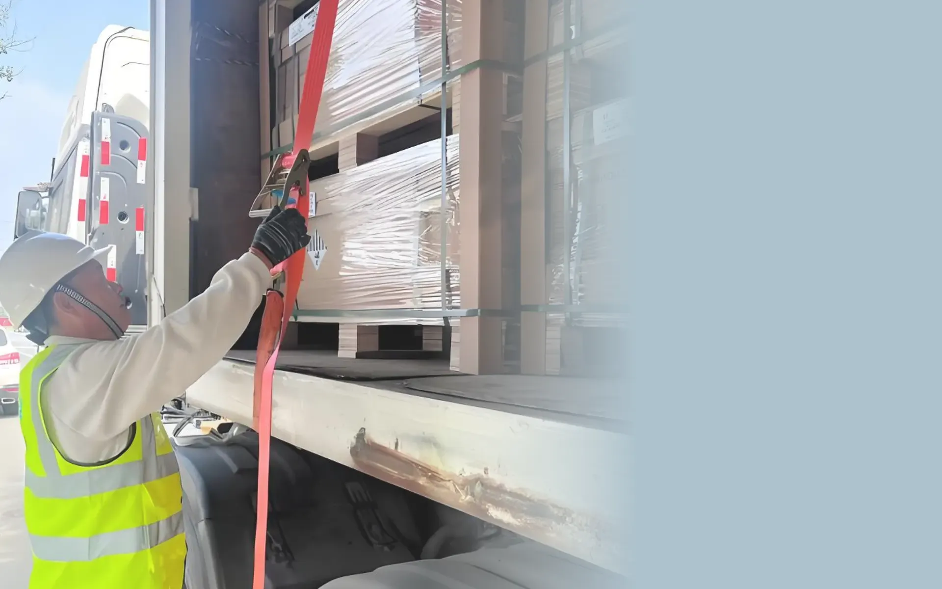 Cargo loading worker fastening a red ratchet strap